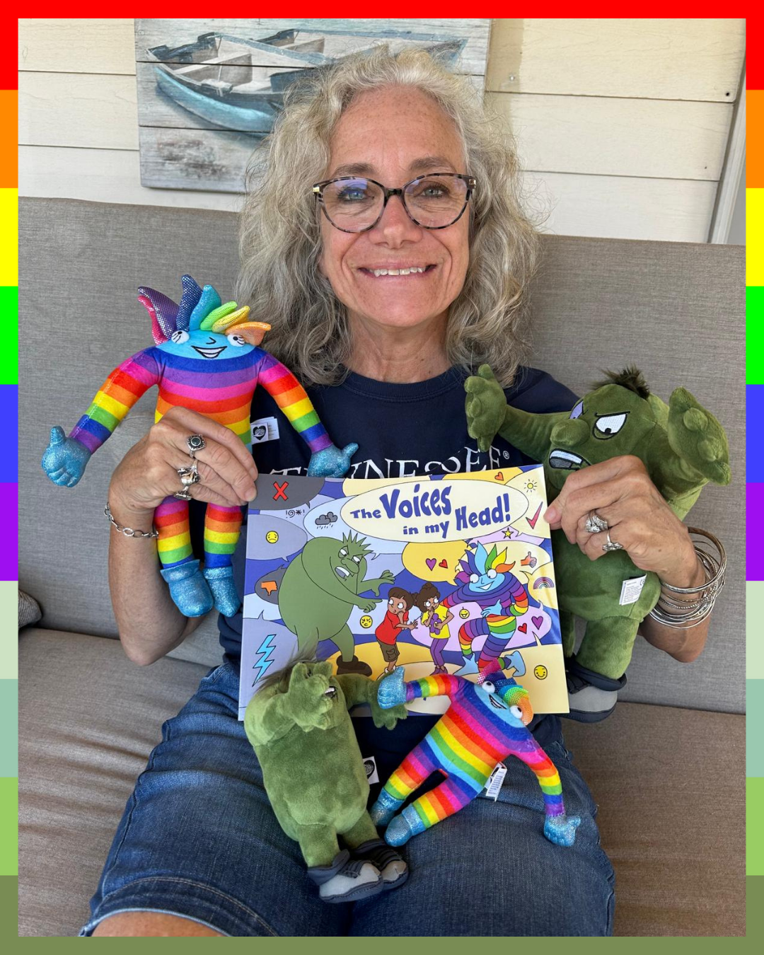 Dr. Karen Bluth holding a book titled 'The Voices in my Head' with colorful plush toys, Booster and Crusher.